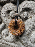 Large Tiger Eye Torus Pendant copper spiral winding rich golden brown chatoyant tiger eye resin 48mm black braided cord stone bail bead Balinese stone wall Batuan Bali front view