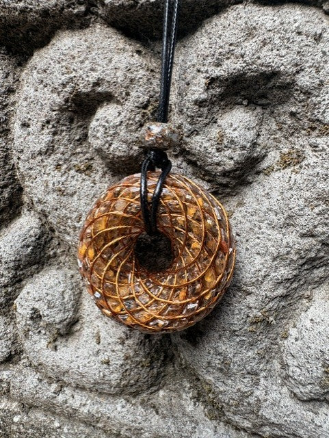 Large Tiger Eye Torus Pendant copper spiral winding rich golden brown chatoyant tiger eye resin 48mm black braided cord stone bail bead Balinese stone wall Batuan Bali front view