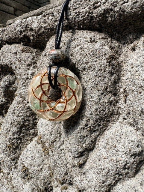 Small Green Aventurine Torus Pendant copper Celtic knot crossover winding pale translucent resin green aventurine chips 33mm black braided cord mixed-stone bail bead Balinese stone wall Batuan Bali front view