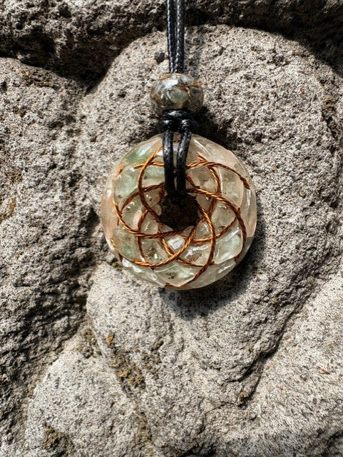 Small Green Aventurine Torus Pendant copper Celtic knot crossover winding pale translucent resin green aventurine chips 33mm black braided cord mixed-stone bail bead Balinese stone wall Batuan Bali close-up