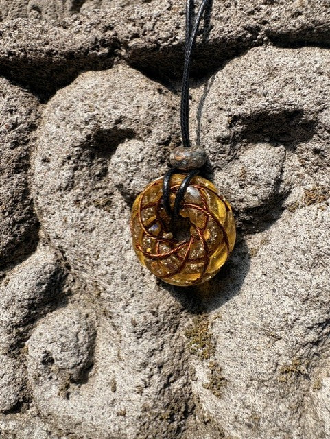Small Yellow Amber Tiger Eye Citrine Torus Pendant copper spiral winding warm golden amber translucent resin 33mm black braided cord stone bail bead Balinese stone wall Batuan Bali front view