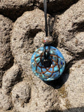 Small Turquoise Torus Pendant copper Celtic knot crossover winding vivid sky blue turquoise resin gold leaf flecks 33mm black braided cord mixed-stone bail bead Balinese stone wall Batuan Bali close-up