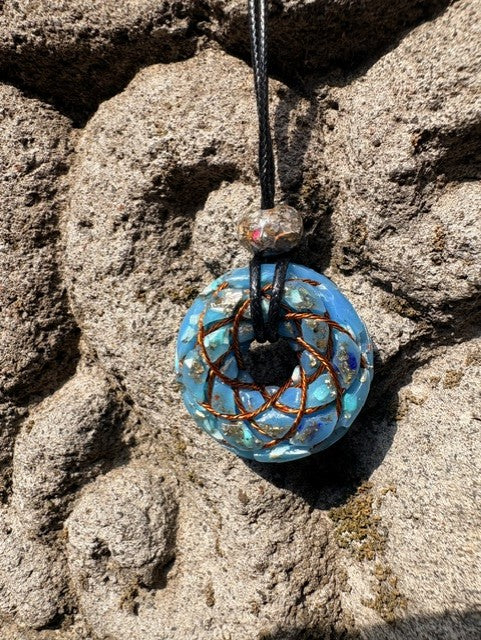 Small Turquoise Torus Pendant copper Celtic knot crossover winding vivid sky blue turquoise resin gold leaf flecks 33mm black braided cord mixed-stone bail bead Balinese stone wall Batuan Bali close-up